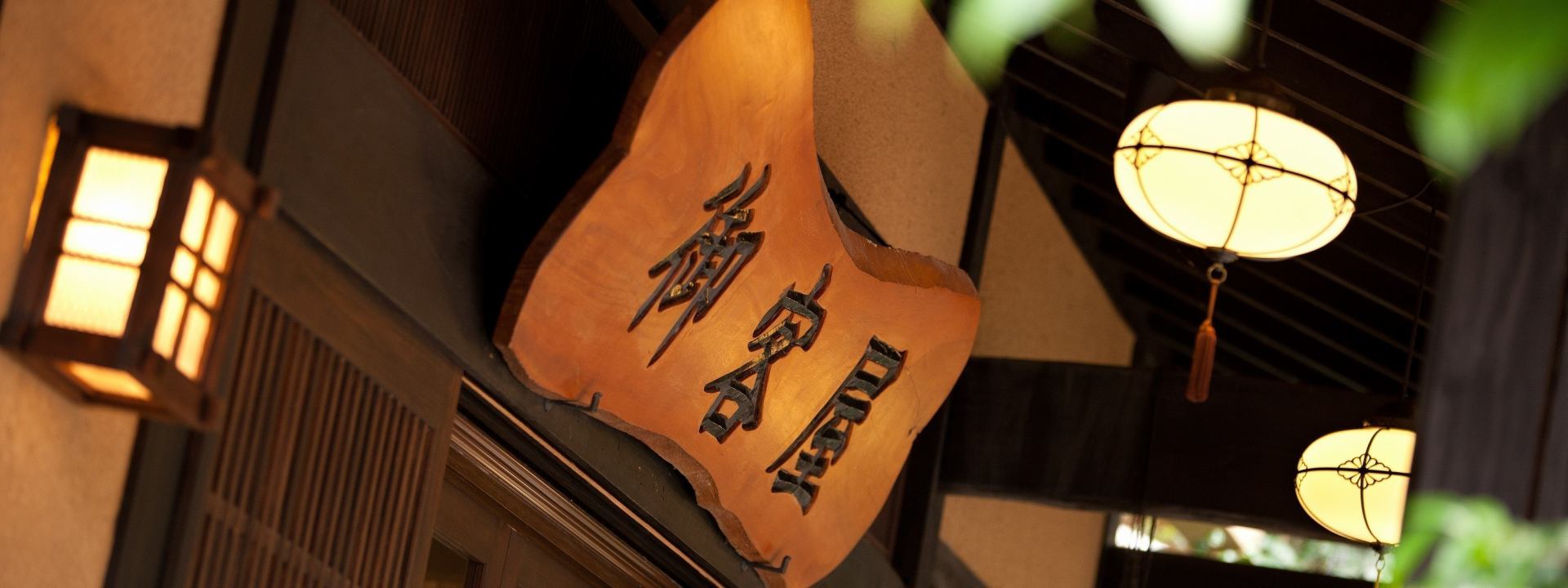 歴史の宿 御客屋 — 一枚板の木彫銘板と灯篭。江戸期から続く宿の意匠