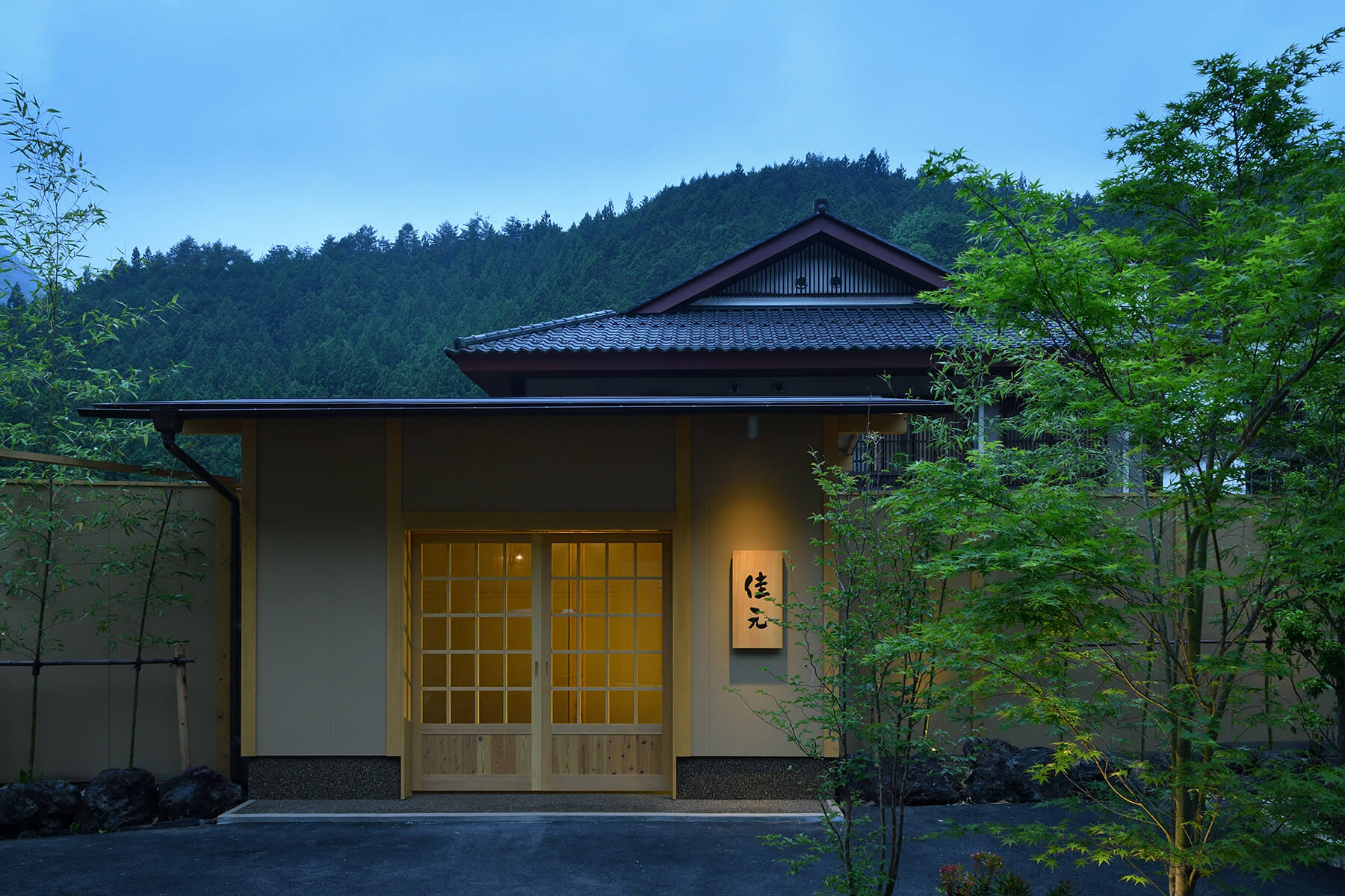 時わすれの宿 佳元 — 四万温泉・ゆずりは地区 · 山を背に佇む数寄屋造りの玄関と夕暮れの灯り