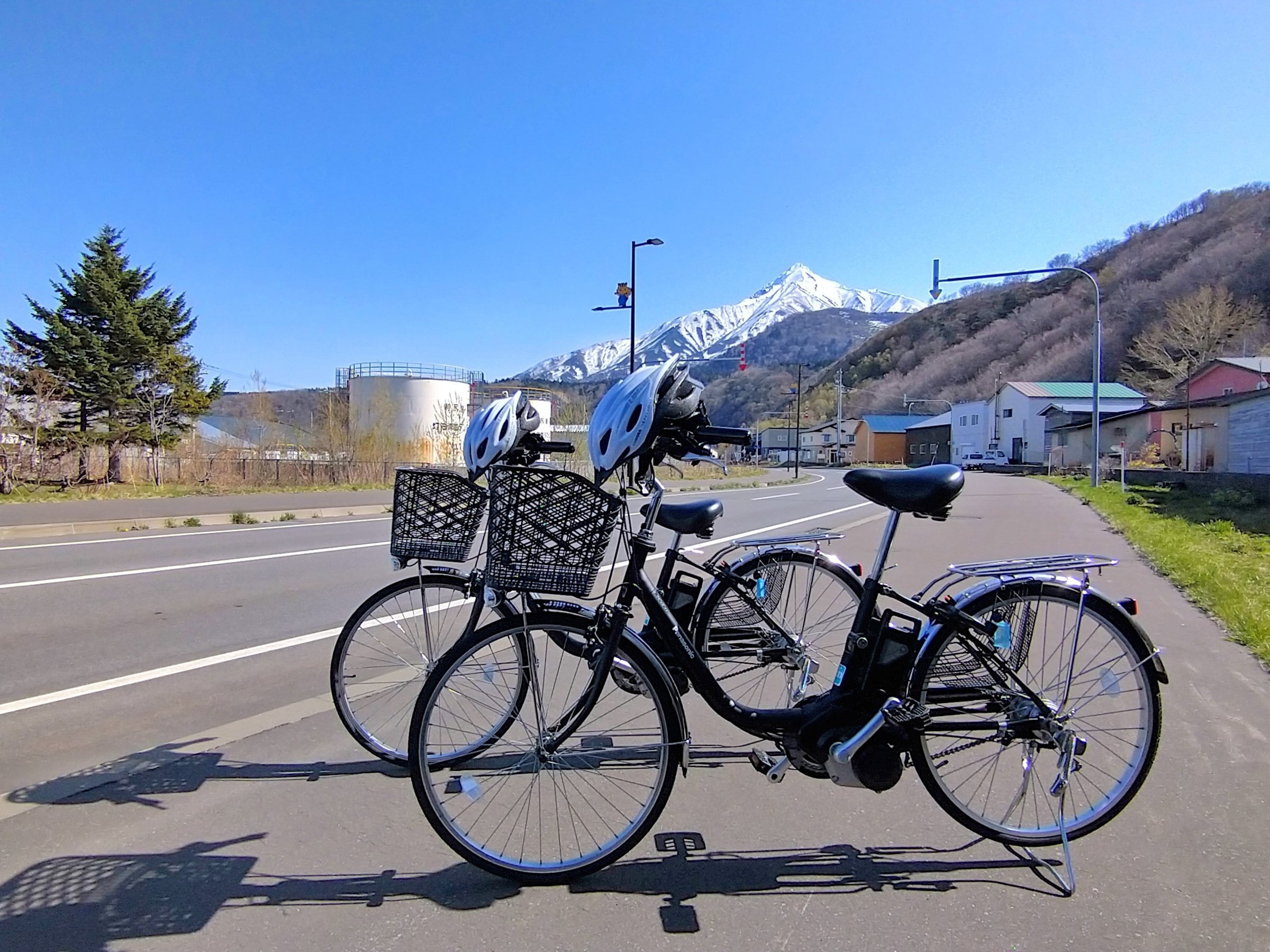 利尻富士観光ホテル — 北海道利尻島・鴛泊 · レンタサイクルの先に雪渓を残した利尻富士が立つ初夏の港町