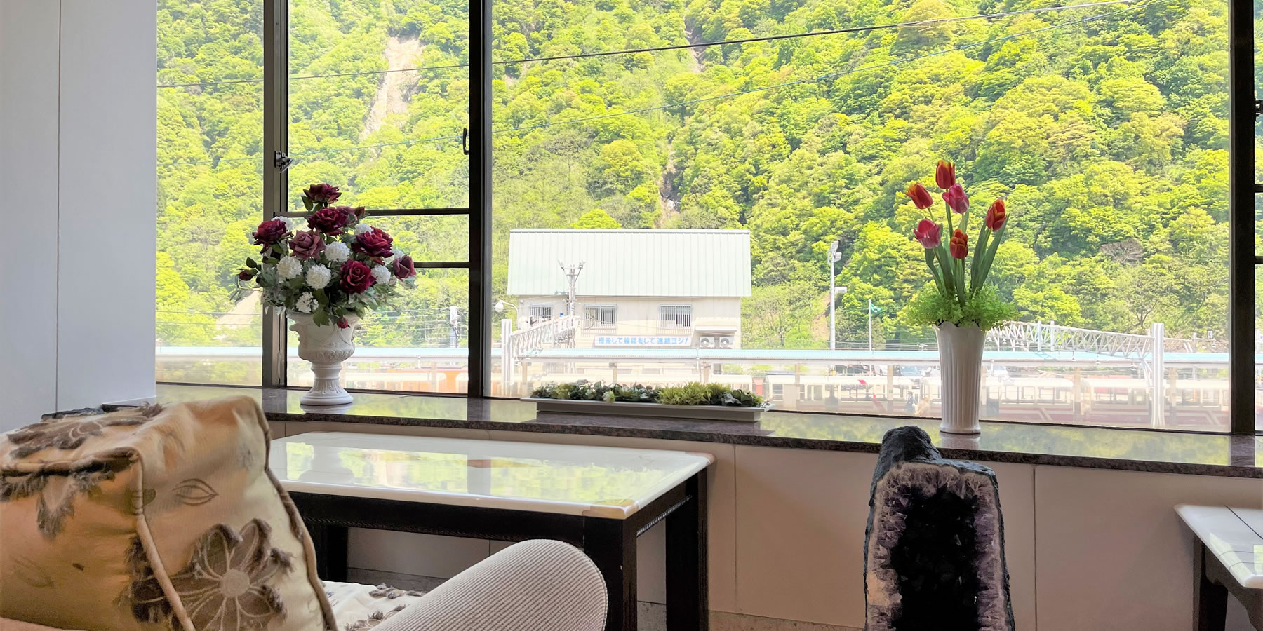 フィール宇奈月 — 黒部市宇奈月温泉 · ロビーから新緑の渓谷とトロッコ宇奈月駅前を望む