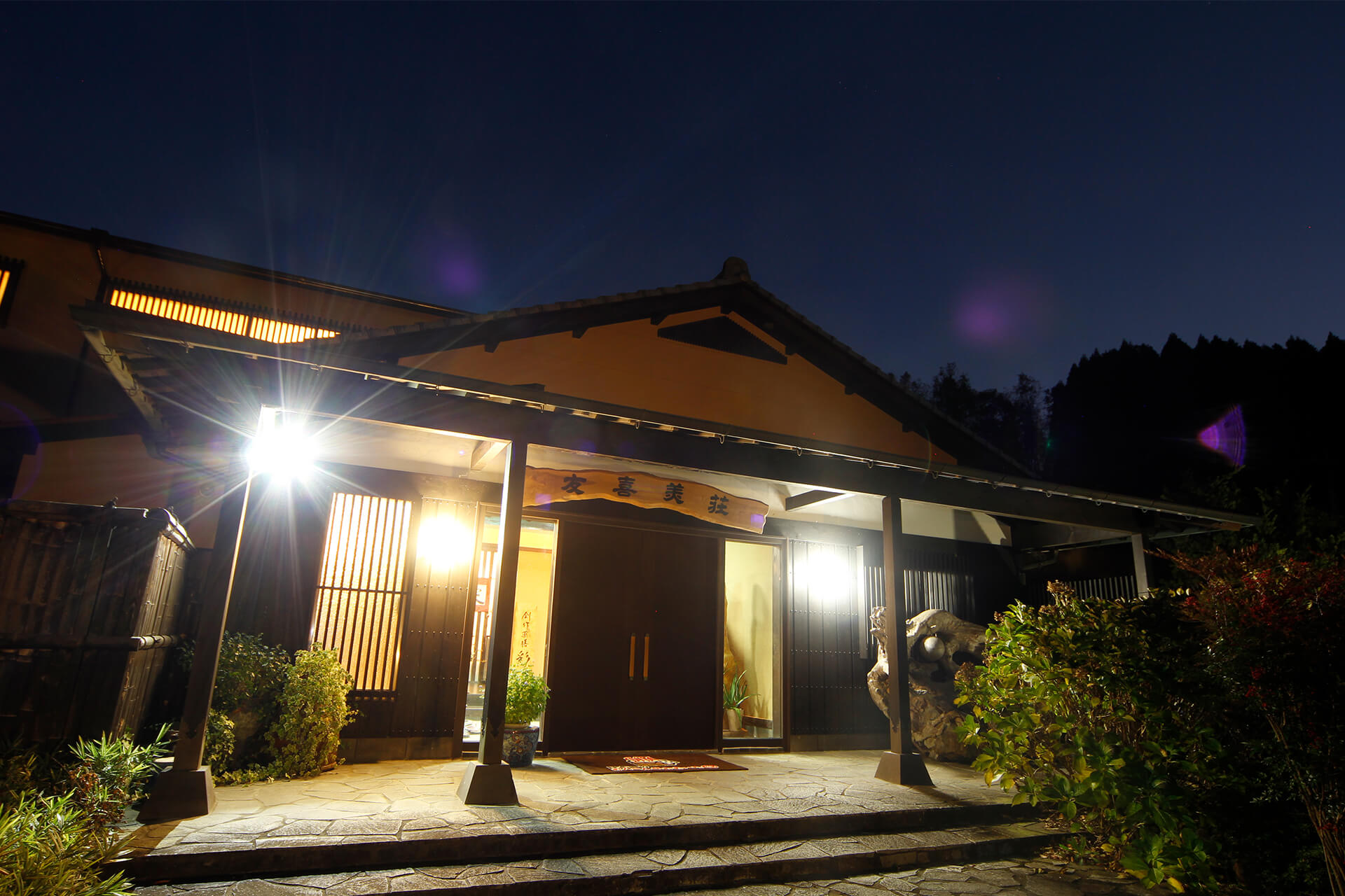 御宿 友喜美荘 — 大分・竹田 長湯温泉 · 木立に囲まれた平屋造りの一軒宿、夜の玄関まわり