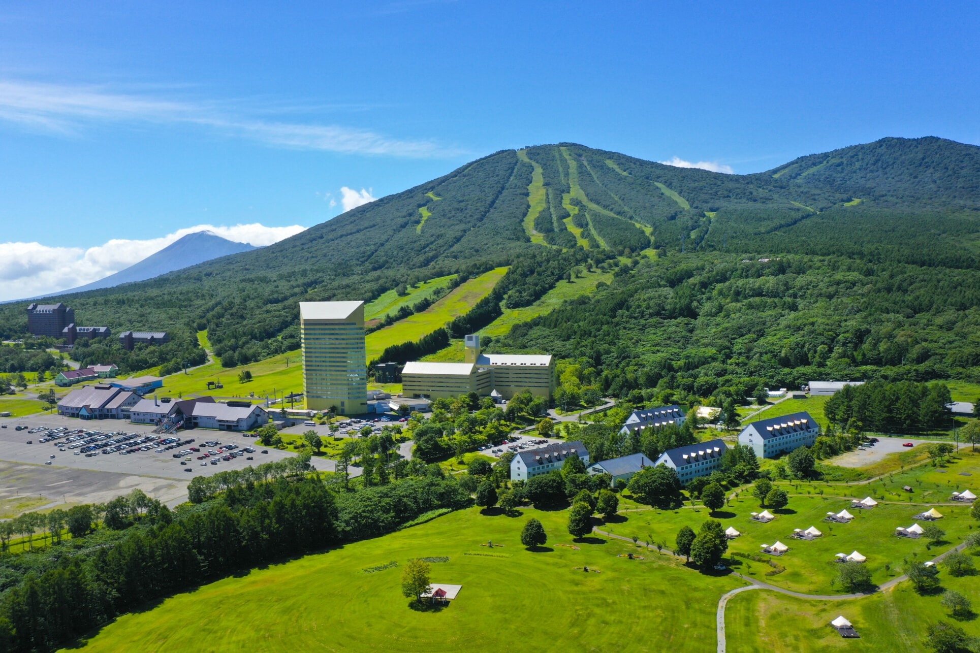 安比高原リゾート全景 — 岩手県八幡平市 · 前森山の斜面とふもとに並ぶホテル群、遠景に岩手山