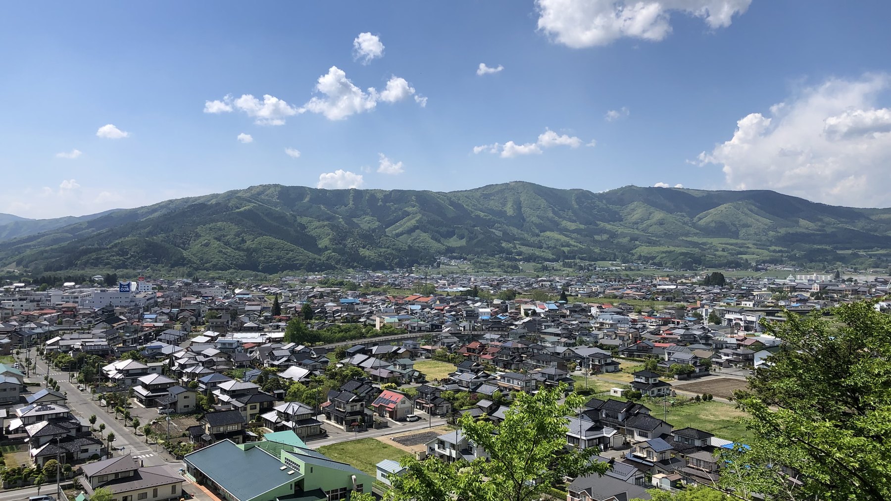 ホテルきくゆう — 岩手県遠野市・遠野駅前 · 高台から見下ろす遠野盆地の街並みと、背後に連なる北上山地の稜線