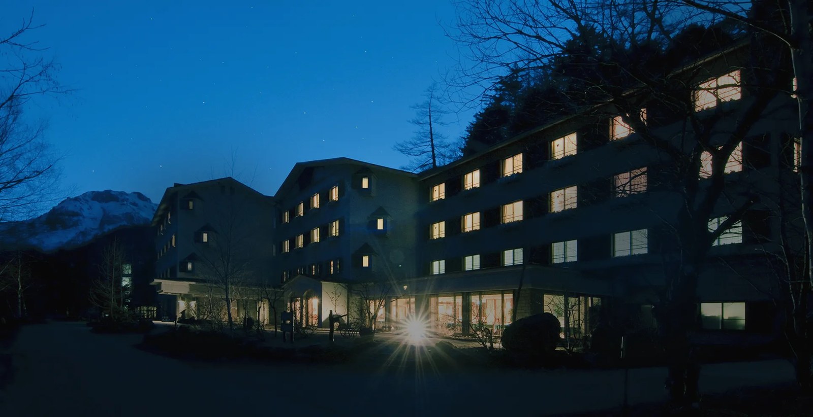 上高地ルミエスタホテル — 長野県松本市安曇・上高地 · 残雪の稜線を背にした夕暮れの外観