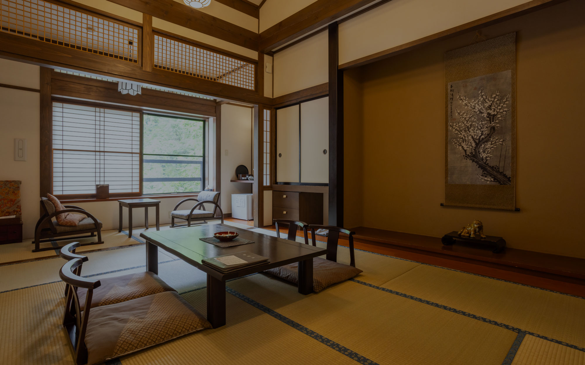能登屋旅館 — 客室 · 床の間と欄間を備えた和室、窓外は銀山の渓