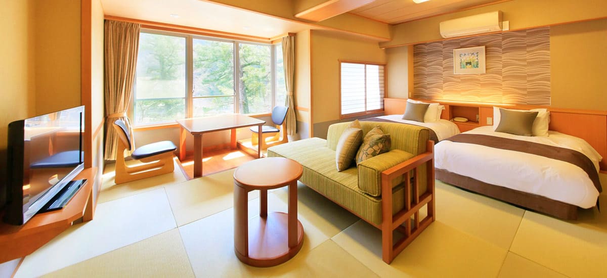 下部温泉 下部ホテル — 山梨・身延町 · 畳敷きにベッドを備えたモダン和風ツインと広縁のテーブル席