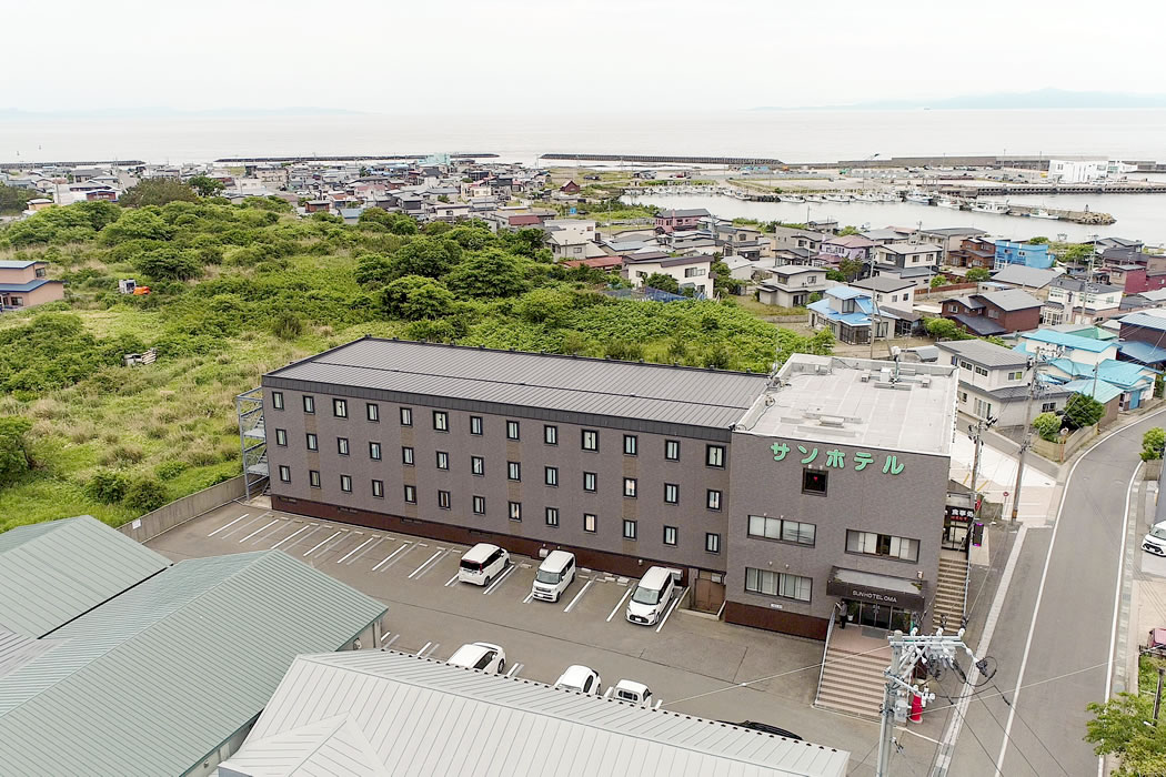 サンホテル大間 — 青森県下北郡大間町 · 大間の漁港と津軽海峡を背にした4階建て外観