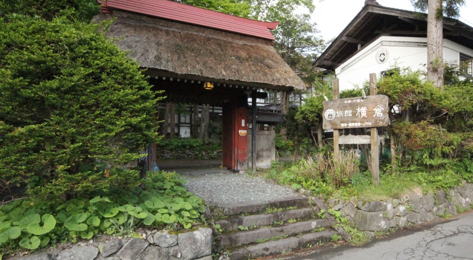 旅館 横倉 宿坊（旧十輪院） — 長野市戸隠中社 · 江戸時代後期に建立された茅葺きの赤門と、白壁の土蔵を望む宿坊の入口