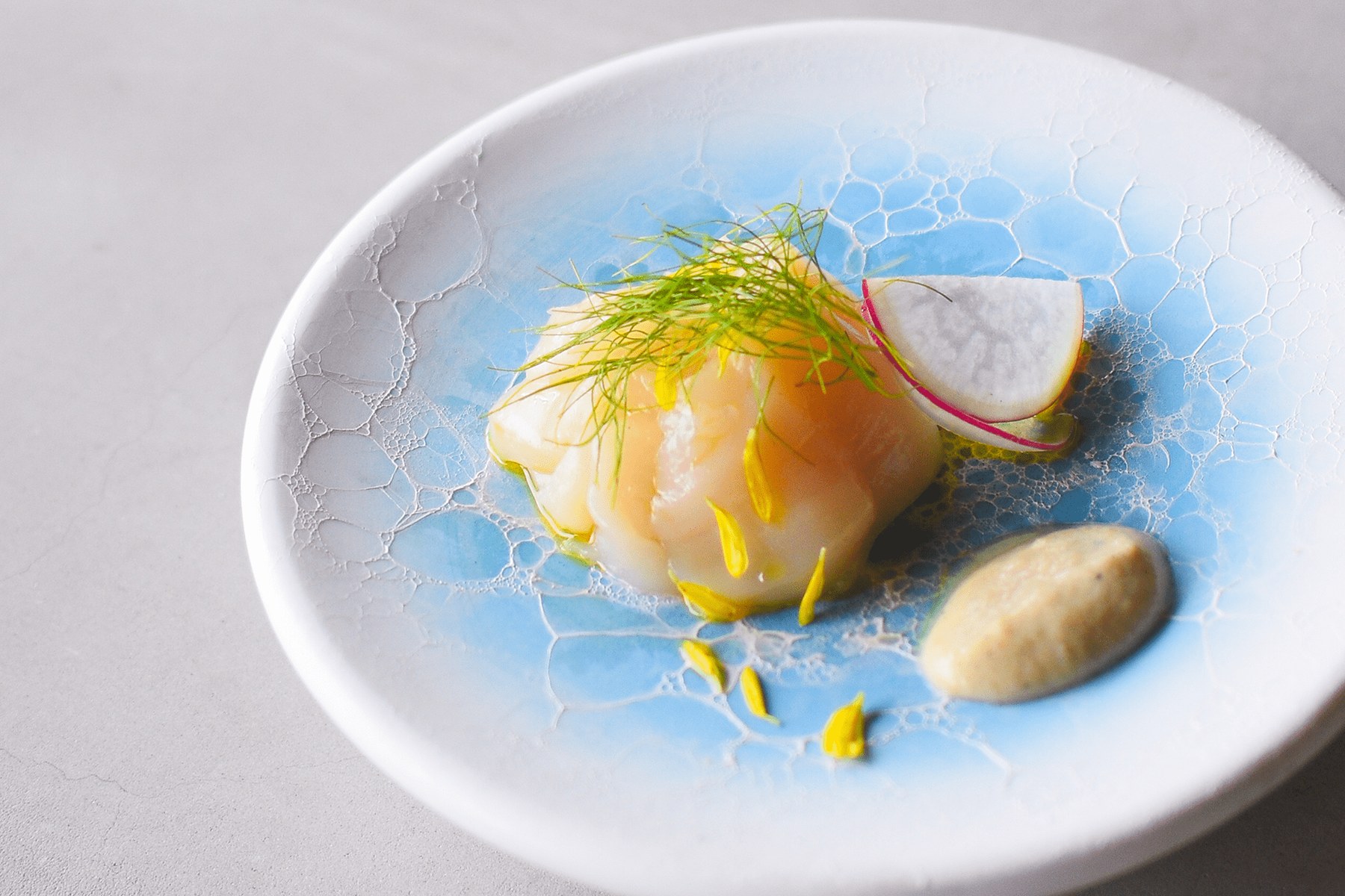 arita huis — 淡い青の釉薬がかかった有田焼の皿に盛られた一品