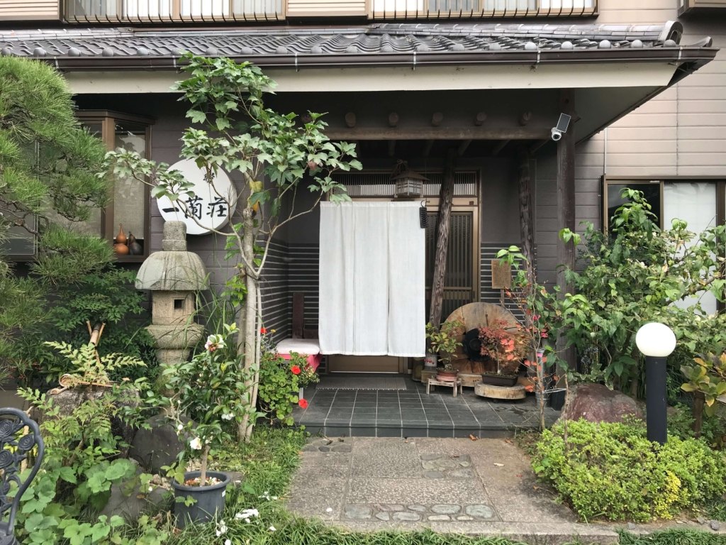 旅館 一蘭荘 — 千葉県香取市佐原 · 小野川ほとりに立つ八室の和風旅館、暖簾と石灯籠のある玄関まわり