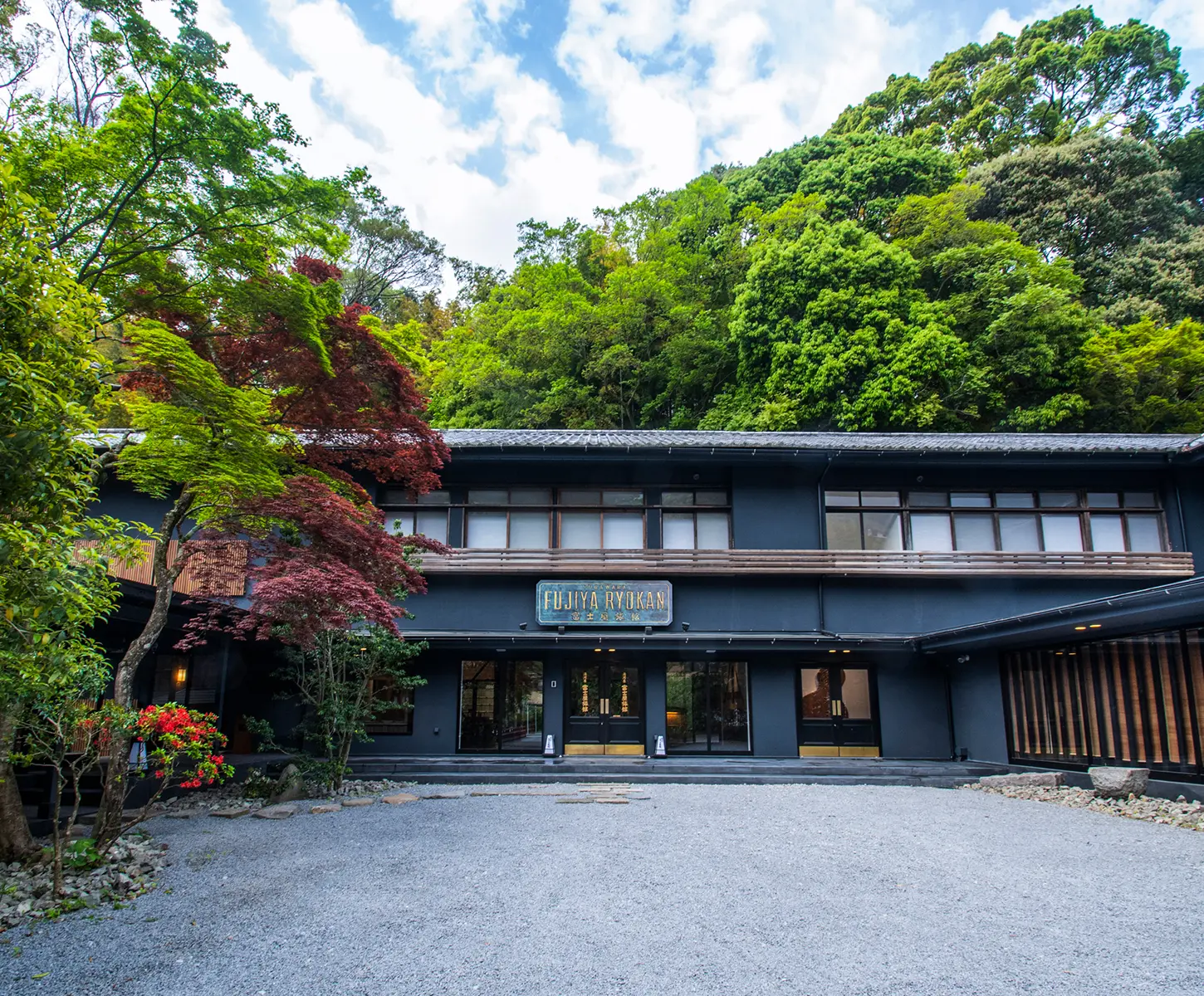 富士屋旅館 — 湯河原・宮上 · 新緑に包まれた黒い外観のエントランス、明治 9 年創業の老舗旅館