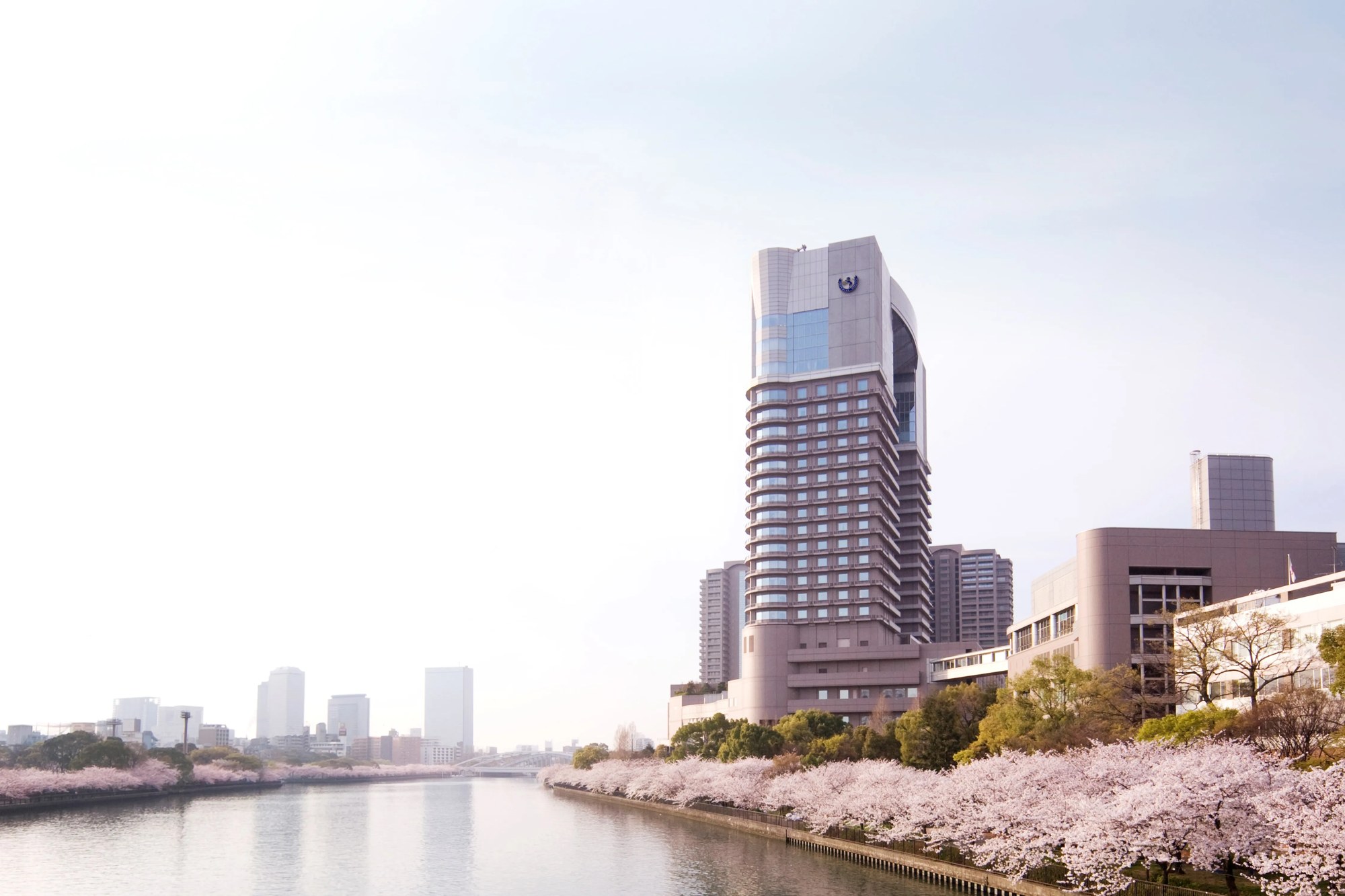 帝国ホテル 大阪 — 大阪・天満橋 · 桜並木の大川越しに望むタワー型の外観