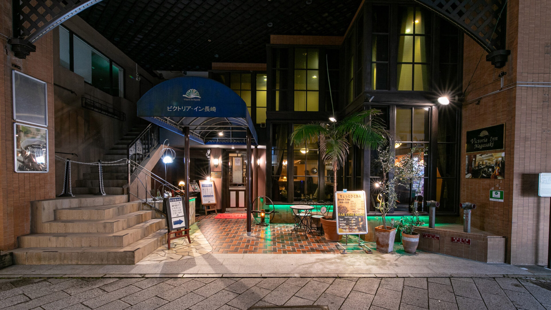 ビクトリア・イン長崎 — 長崎・銅座町 · 青い庇とカフェ&バーのある夜のエントランス