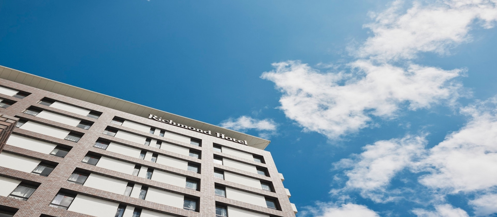 リッチモンドホテル長崎思案橋 — 長崎市本石灰町 · 青空を背に見上げたレンガ調の外観