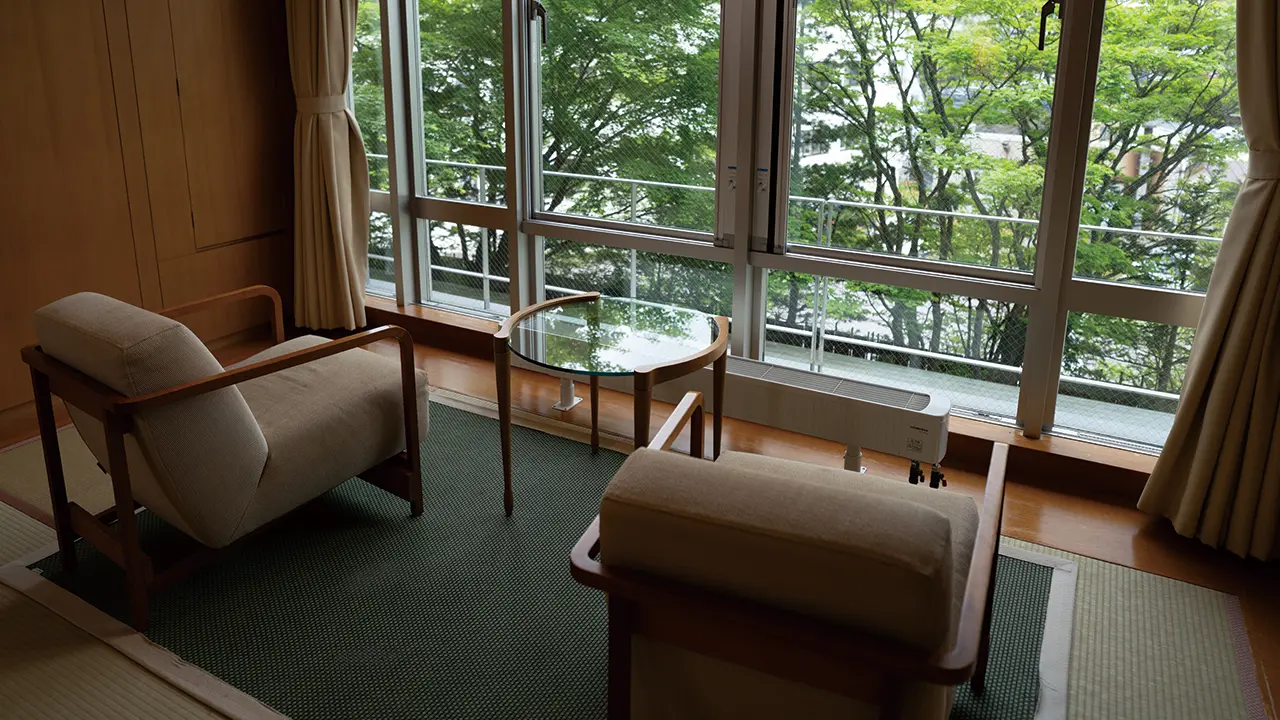 草津温泉 望雲 — 群馬・草津町 · 畳に肘掛け椅子を据えた客室から新緑を望む、創業1598年の老舗旅館