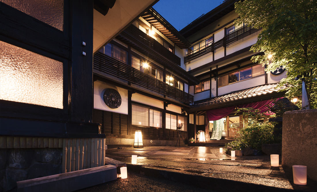 深山荘 高見屋 — 山形市蔵王温泉 · 薄暮に灯りがともる木造建築の玄関前と行灯