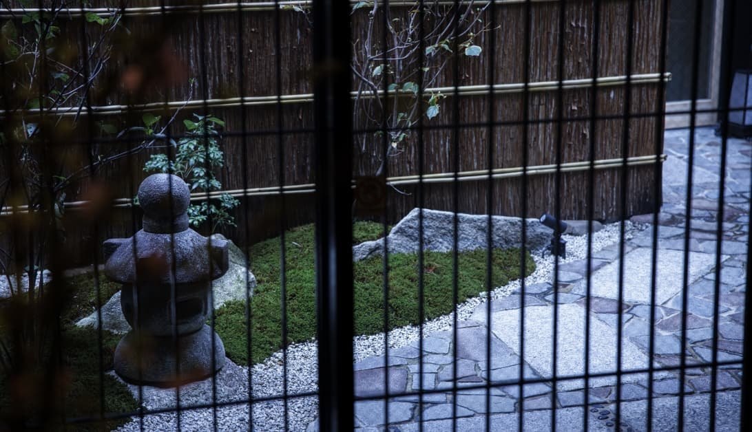 旅情の宿 ホテル金澤草紙 — 金沢市安江町 · 石灯籠と苔を配した館内の坪庭、格子越しの眺め