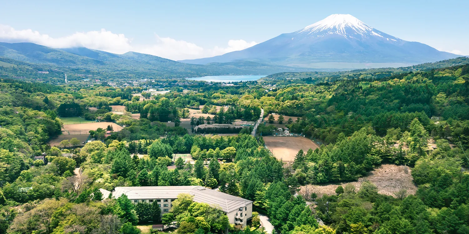 富士マリオットホテル山中湖 — 山梨県山中湖村 · 森に囲まれた建物の奥に山中湖と富士山を望む空撮