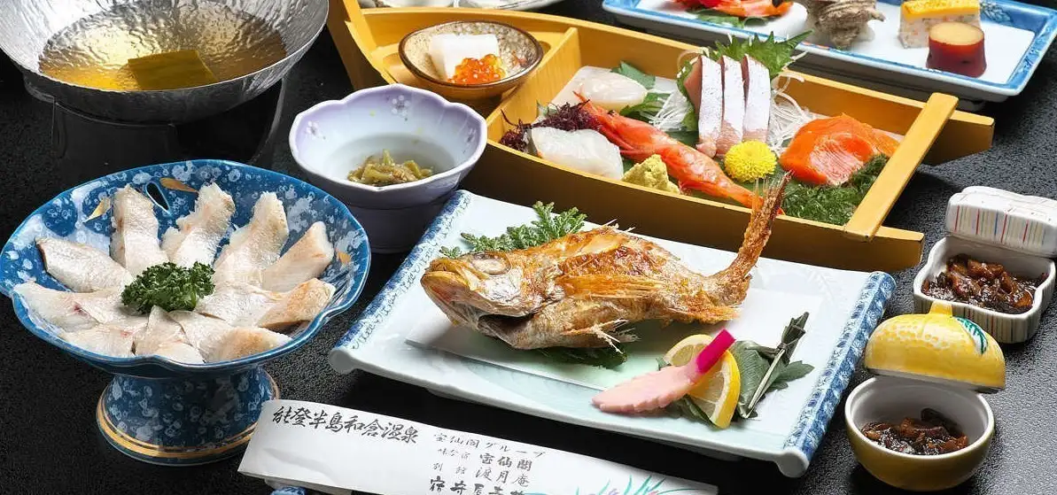 味な宿 宝仙閣 — 石川県七尾市・和倉温泉 · 舟盛りと焼き魚が並ぶ夕食の会席料理