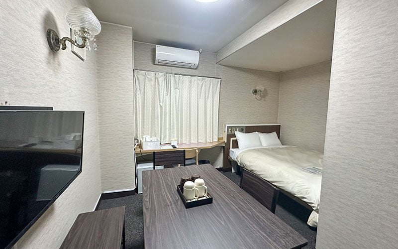 ホテル延岡ヒルズ — 宮崎県延岡市紺屋町 · ベッドとテーブル、壁掛けテレビを備えた客室