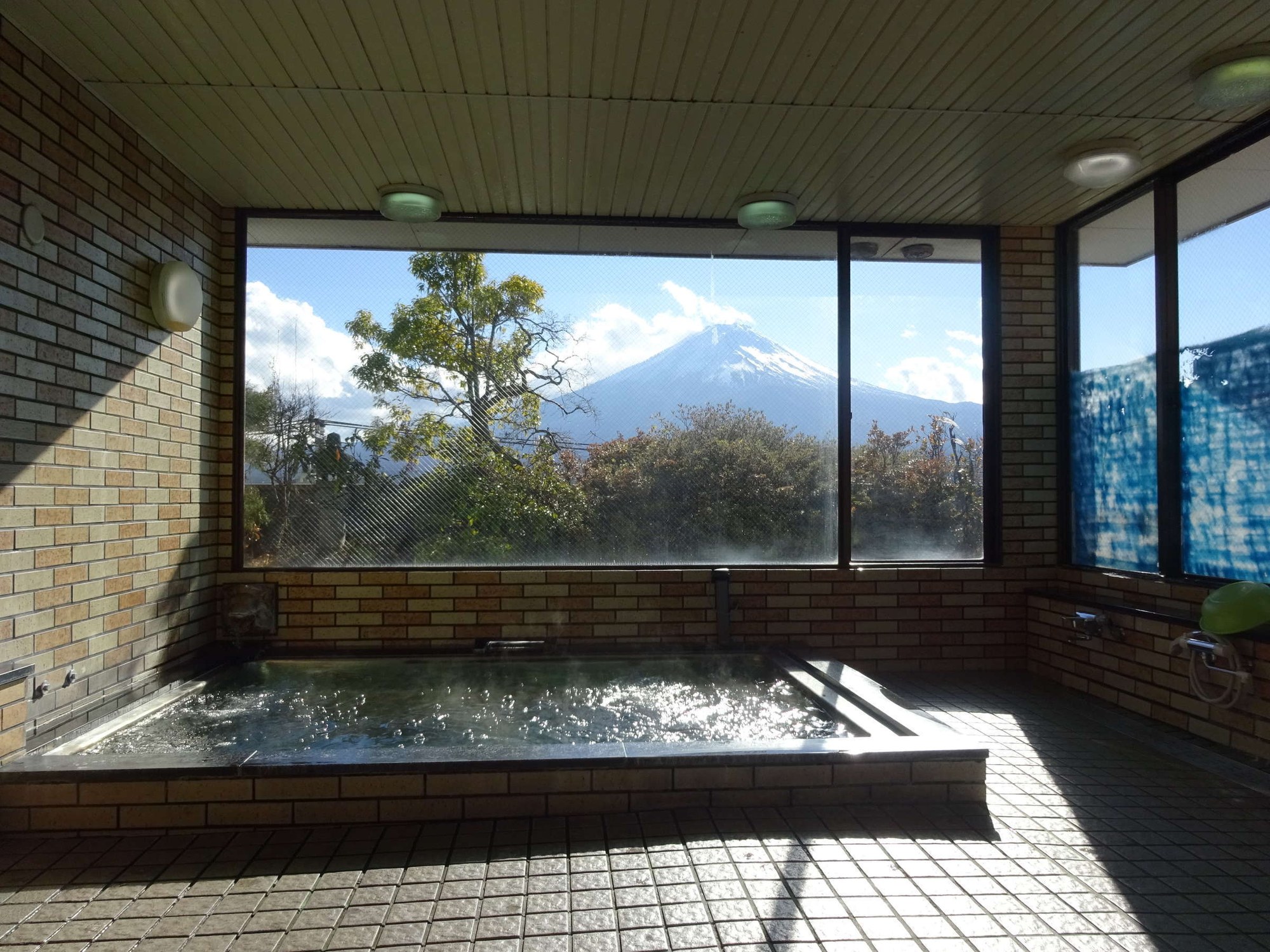 河口湖ステーションイン — 山梨県富士河口湖町・河口湖駅前 · 4階の展望風呂の窓越しに富士山を望む全15室の宿