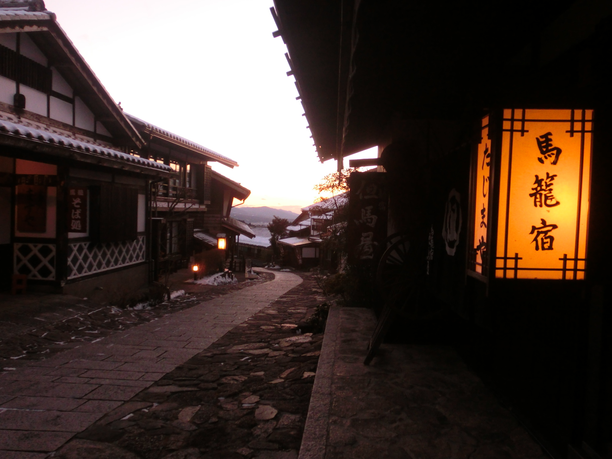 旅人御宿 但馬屋 — 岐阜県中津川市・馬籠宿 · 夕暮れの石畳の坂道と但馬屋の行灯看板